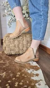 Botinetas de cuero napa color tostado, con taco bajo de madera de 3 cm, elástico lateral y panel trasero con textura de símil piel de serpiente. Cuentan con un cierre lateral decorativo y funcional.