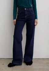 Pantalón de jean negro de corte recto y tiro medio, con cierre frontal de botón y cremallera, y bolsillos laterales y traseros.