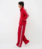 Pantalón deportivo de corte recto y holgado, color negro con rayas blancas laterales. Cuenta con cintura elástica con cordón ajustable, bolsillos laterales y detalle de costura vertical frontal.