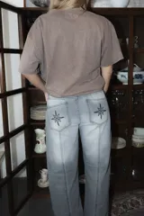 Jean de corte recto y tiro medio, con costuras verticales decorativas en el frente y bordado de brújula en los bolsillos traseros.