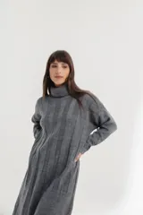 Vestido midi de tejido de punto color crema, con cuello alto, mangas largas y corte recto con aberturas laterales.