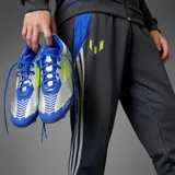 Championes de fútbol Adidas modelo F50 League FG edición Messi, con diseño en azul, plateado y detalles en amarillo neón. Presentan una estructura ligera con cordones y suela con tapones para terreno firme.