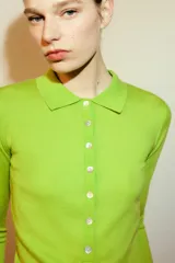 Jersey de punto fino confeccionado en lana, con cuello polo, cierre frontal de botones y manga larga.