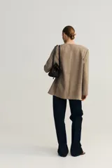 Blazer de sarga sin solapas color marrón, con hombreras, frente abierto, pinzas en la cintura, bolsillos delanteros ribeteados y forro interior.