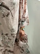 Vestido largo rosado con estampado floral en tonos marrones y beige, cuello drapeado y mangas largas holgadas.