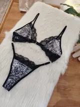 Conjunto de lencería compuesto por corpiño triangular y bombacha tipo tanga. El diseño combina microtul con estampado animal print y detalles de encaje negro en los bordes. El corpiño cuenta con cierre frontal y breteles regulables.