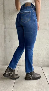 Jean de calce recto con lycra, color azul medio, con bolsillos delanteros y traseros.