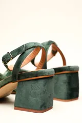 Sandalia de tacón cuadrado medio, confeccionada en terciopelo negro. Presenta un diseño de tiras cruzadas con nudo en la parte delantera y una tira ajustable con hebilla en el tobillo.