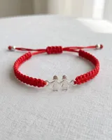 Pulsera de hilo rojo trenzado en macramé, con dije central de plata 925 con diseño de dos nenas tomadas de la mano y cierre regulable.