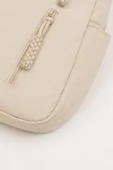 Cartera tipo hobo de nylon color beige, con correa ajustable para el hombro, cierre principal superior y dos bolsillos frontales verticales con cierre y tiradores trenzados. Cuenta además con bolsillos laterales abiertos.
