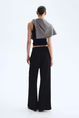 Pantalón negro de tiro alto, confeccionado en tejido texturizado con corte holgado y piernas amplias. Cuenta con cintura elástica fruncida y cordón ajustable.
