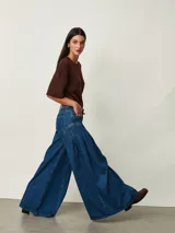 Jean de denim azul de tiro medio, con diseño wide leg de corte muy amplio y pinzas laterales decorativas que aportan volumen.