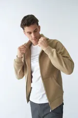 Campera de felpa color blanco hueso, con capucha y cordón ajustable, cierre frontal con cremallera, bolsillos laterales, logo y arte estampado en el pecho.