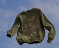 Buzo cropped de algodón color verde militar, con mangas ranglan y diseño estampado en el frente con motivos de besos y moños. Cuenta con elástico holgado en la cintura y los puños.