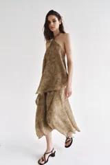 Falda midi de tiro alto y diseño asimétrico con cierre frontal cruzado y botón decorativo. Presenta una textura rústica con estampado sutil y forro interior marrón.