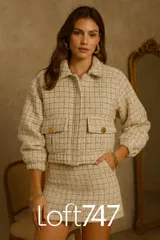 Chaqueta corta de tweed en tonos neutros con entramado a cuadros, cuello clásico y cierre frontal con cremallera. Cuenta con bolsillos de solapa con botones dorados en la parte delantera y mangas largas con puños elásticos.