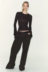 Camiseta de cuello redondo y manga larga, confeccionada en tejido rib con mezcla de lyocell. Presenta un diseño ajustado con terminación de volantes en los puños y bajo recto.