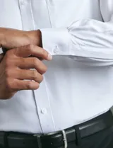 Camisa de vestir de manga larga en color azul claro, con cuello clásico, cierre frontal de botones y bolsillo en el pecho.