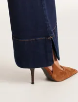 Jean wide leg azul oscuro de tiro alto, con pierna ancha y ruedo con tajo lateral. Presenta pretina con pasadores, botón y cierre, y bolsillos delanteros y traseros.