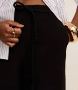 Pantalón tipo pantacourt de corte sastre, color rojo oscuro o vino, con talle alto y lazo ajustable en la cintura. El tejido es ligero y fluido.