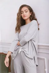 Remerón de tela acanalada color gris, con corte holgado, mangas tres cuartos y aberturas laterales en el ruedo.