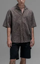 Camisa de manga corta con calce oversize y cuello abierto, confeccionada en algodón con diseño de bordado tipo broderie y efecto de desgaste en el color.