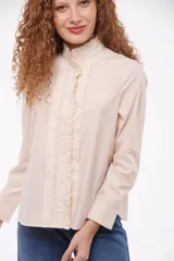 Camisa color blanco con cuello alto con volados y cierre frontal con botones ocultos.