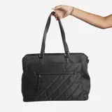 Bolso tipo tote negro con diseño acolchado en diagonal, doble asa de mano y cierre superior.