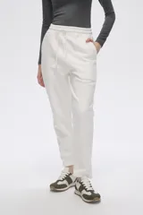 Pantalón tipo babucha de felpa color blanco, con cintura elástica ajustable mediante cordón y bolsillos laterales.