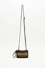 Cartera pequeña tipo bandolera de cuero vacuno negro, con detalle frontal de lentejuelas doradas. Cuenta con correa larga ajustable y extraíble, y una manija lateral corta para llevar en la muñeca.