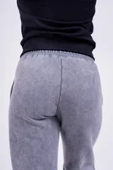 Pantalón de jogging gris con efecto lavado, corte holgado y logo bordado en negro.