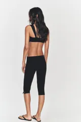 Pantalón capri de tiro medio confeccionado en tejido elástico, con cierre lateral mediante cremallera oculta.