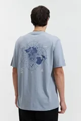 Remera de manga corta color celeste claro con cuello redondo y un estampado gráfico en la espalda que simula un mapa polar con coordenadas y texto.