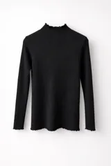 Media polera de manga larga en color negro, confeccionada en tejido de punto con trama vertical. Presenta un cuello alto y terminaciones con borde ondulado en cuello, puños y ruedo.