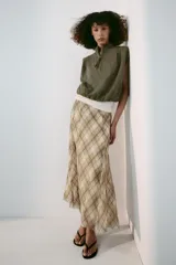 Falda midi de tiro alto, con estampado de cuadros en tonos beige y marrón, costuras marcadas y cierre lateral con cremallera oculta.