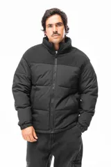 Campera puffer negra con diseño de paneles, cierre frontal completo y cuello alto. Presenta una textura diferenciada en la parte superior y bolsillos laterales.