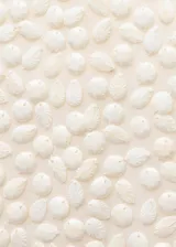 Vestido corto de corte recto y sin mangas, con cuello redondo. Presenta una superficie completamente cubierta de abalorios decorativos de plástico con acabado nacarado y cierre de cremallera invisible en la parte posterior.