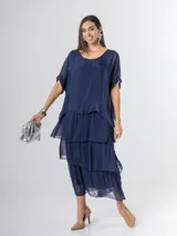 Vestido largo azul marino de seda italiana, con diseño de volados escalonados en la falda y una sobrecapa superior con mangas cortas amplias.