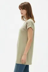 Remera de algodón negra, de corte holgado, con cuello redondo a la base y detalle de estampado floral en el hombro izquierdo.