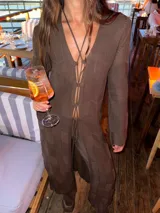 Saco largo de tejido de punto color marrón, con diseño de textura geométrica, mangas largas y cierre frontal mediante cordones ajustables.