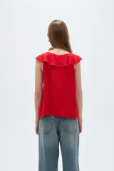 Blusa negra de viscosa sin mangas, con cuello redondo, volados frontales y detalle de lazo en el escote.