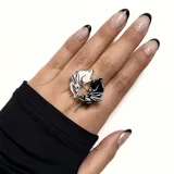 Anillo plateado con diseño de dos conejos, uno blanco y otro negro, formando un círculo.