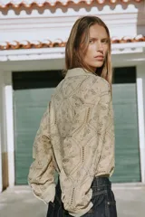 Camisa de cuello solapa con escote en V, manga larga y cierre frontal con botones. Presenta un diseño con bordados perforados en todo la prenda.