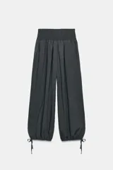 Pantalón baggy de tiro medio color rosado, con cintura elástica fruncida tipo nido de abeja y bajos ajustables con cordones.