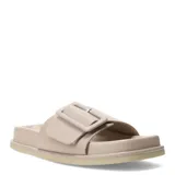 Sandalias tipo slide color beige, con tira ancha frontal y hebilla decorativa cuadrada al tono. Presentan una suela plana con plataforma baja y diseño ergonómico.
