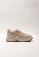Zapatilla acordonada color beige con plataforma irregular y bicolor de 5 cm de alto. Presenta un diseño con varios cortes y texturas.