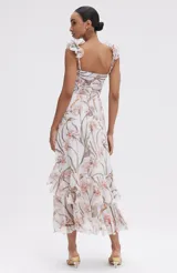 Vestido midi con estampado floral en tonos suaves, escote con volantes y falda vaporosa con abertura frontal.