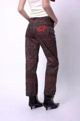 Pantalón de corte recto y largo al tobillo, con estampado de espiga en tonos oscuros y líneas rojas. Presenta tiro medio y cierre frontal.