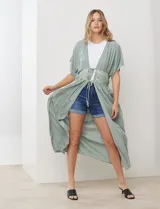 Kaftan largo color verde salvia, con mangas cortas y detalle de puntilla bordada en el área del busto y cintura. Posee un lazo ajustable en el centro del frente.