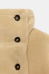 Cazadora reversible de cuello subido y manga larga, con bolsillos de vivo en el delantero y cierre frontal con botones. Confeccionada en tejido combinado con efecto pelo y efecto ante.